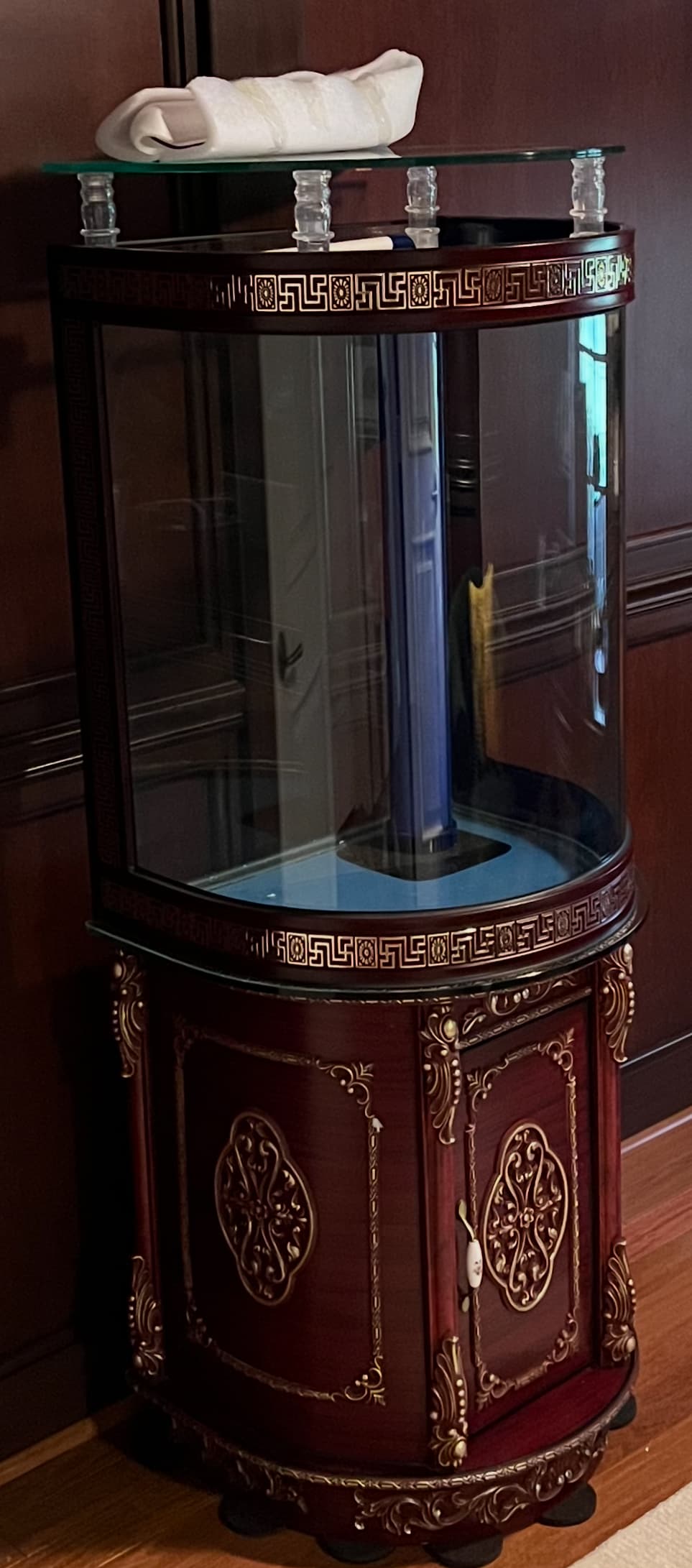 Ornate dark wood corner aquarium featuring gold Greek key patterns and intricate filigree base carvings.